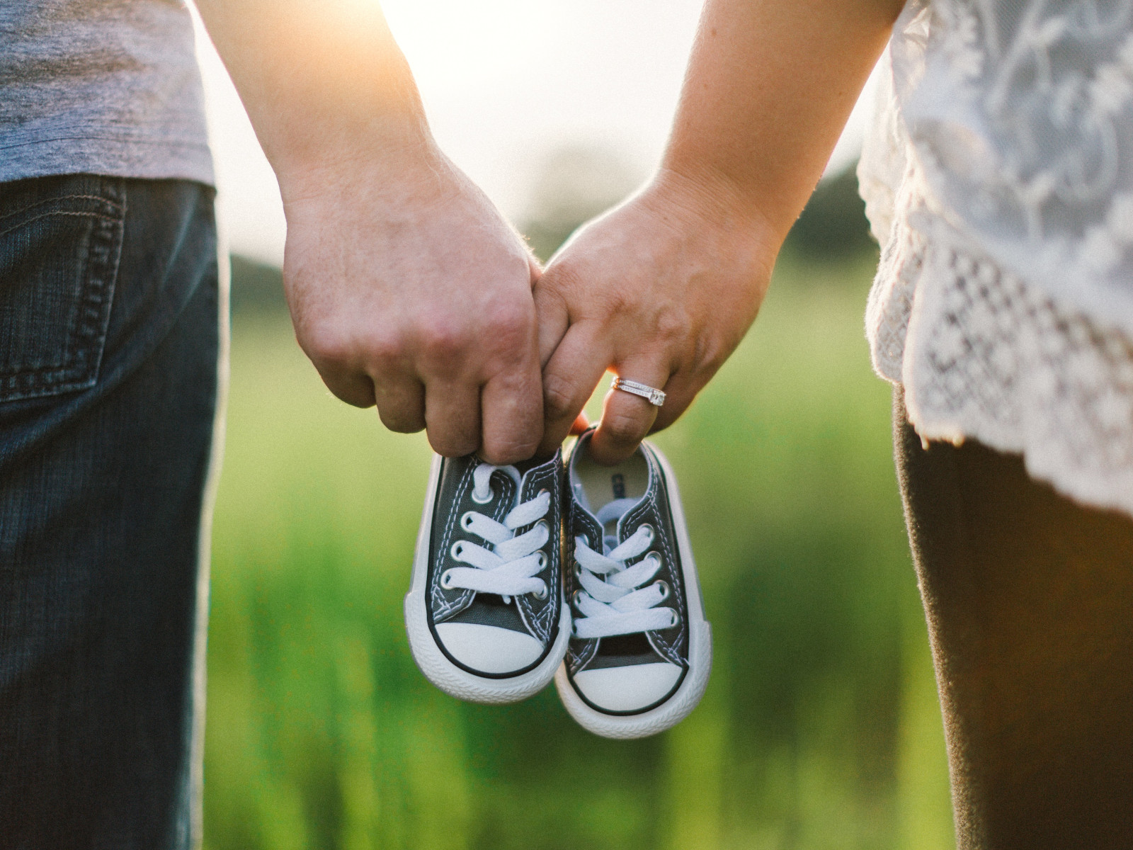 Parents holding hands and baby Converse shoes