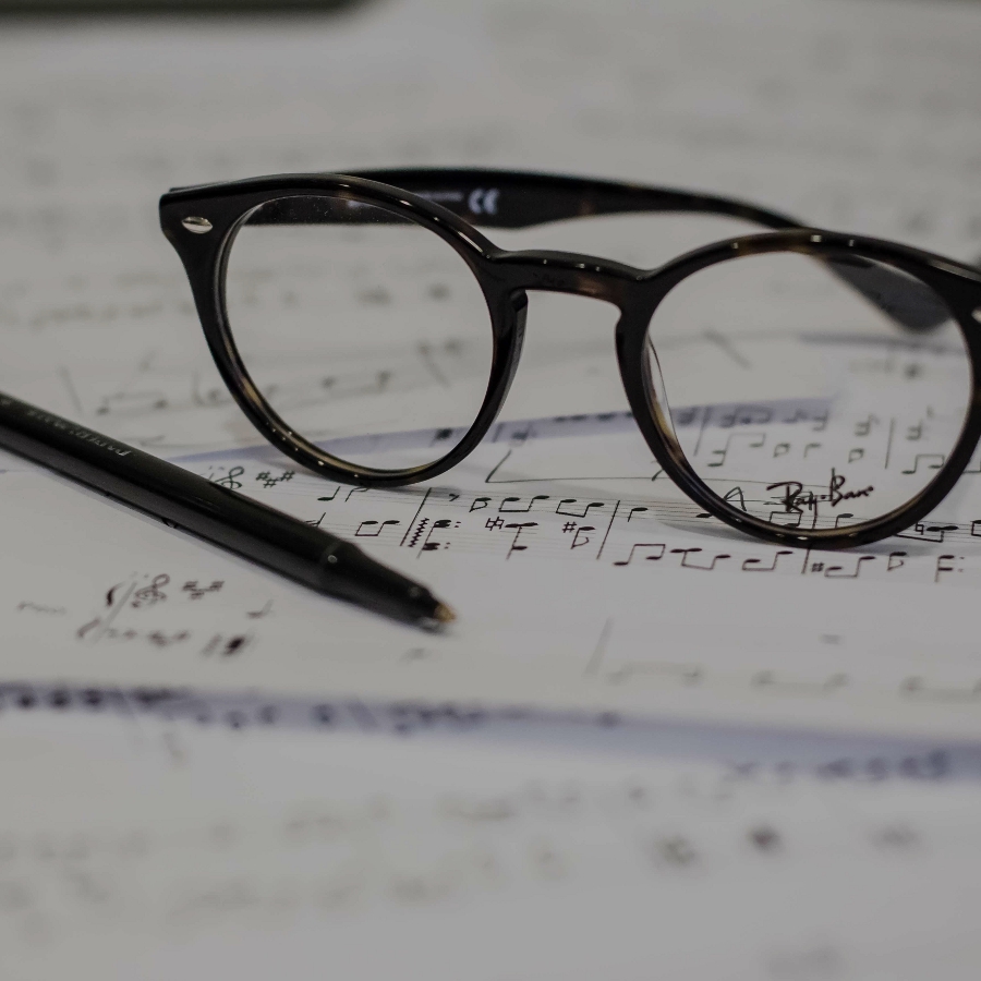 Glasses and pen atop sheet music (Credit: Dayne Topkin via Unsplash)